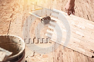 Wood Flooring Installation. worker installing wood parquet. Carpenter on work putting wood parquet pieces