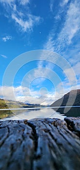 wood in the foreground with lake and mountains in the background photo