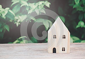 Wood house model on table  with green nature blur Background and sunray. Savings Plans for Housing. Finance and Banking