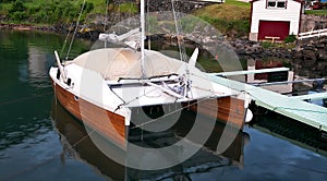 Wood hull catamaran sailboat tied to a dock