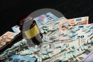 Wood judge`s gavel and scattered colorful drugs on the dollar an