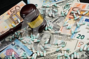Wood judge& x27;s gavel and scattered colorful drugs on the dollar and euro cash background