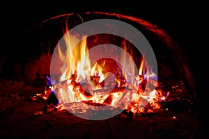 Wood logs are engulfed in flames, radiating heat and light