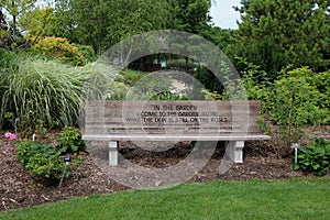 A wood memorial bench engraved with a quote surrounded by plants at the Rotary Botanic Gardens in Wisconsin