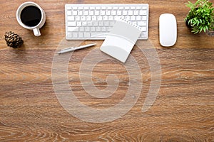 Wood office desk table with computer keyboard with mouse, blank notebook, cup of coffee and supplies. Top view with copy space,