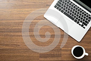 Wood office desk table with laptop computer and a cup of coffee. Top view with copy space, flat lay