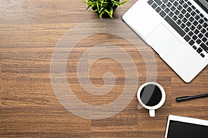 Wood office desk table with laptop, a cup of coffee and supplies. Top view with copy space, flat lay