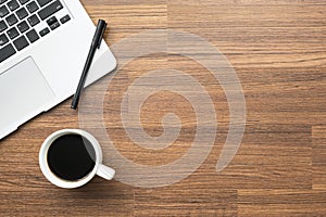 Wood office desk table with laptop, pen and cup of coffee. Top view with copy space, flat lay