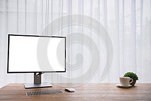 Wood office table with blank screen on monitor computer screen and coffee cup on white curtain window texture background