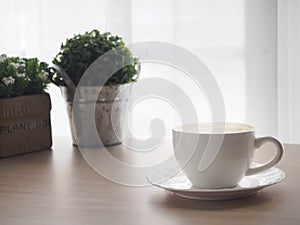 Wood office table with cup of latte coffee and beautiful flower