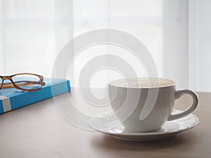 Wood office table with cup of latte coffee and modern eyeglasses