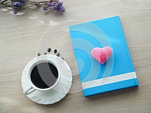 Wood office table with hot black coffee cup, dried purple flower