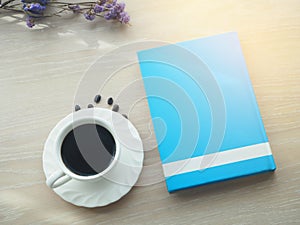 Wood office table with hot black coffee cup, dries purple flower