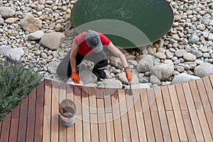 Wood oil application, workwoman maintaining exterior house garden terrace