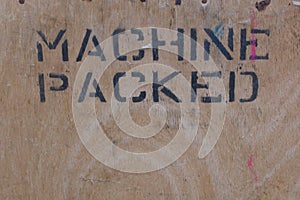 Wood panel with the words machine packed stencilled in black