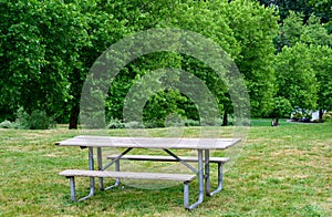 Wood picnic table on a grass lawn in a peaceful green landscape