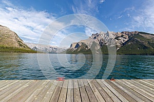 Wood pier at Minnewanka lake with Girouard mountain and blue sky in summer background