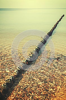 Wood pilings on beach, vintage retro effect