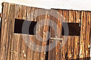 Wood, plank shed doors, with two cut outs for glassless windows to a wine cellar