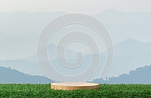 Wood podium table top on fresh green grass with outdoor mountains scene nature landscape at sunrise blur background.Natural beauty