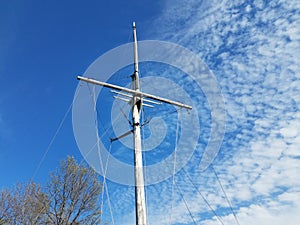 Wood pole boat mast with cables and blue sky
