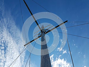 Wood pole boat mast with cables and blue sky