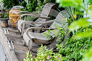 Wood rocking chairs in a cottage garden porch setting on wooden floor in vintage Thai botanical garden, with traditional Thai wate