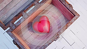 Wood and rusty metal Chest put on an old floor which is opening on a very big and chubby red heart