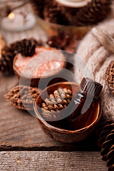 Wood scents for winter time aromatherapy. Pine cones, candles, essential oil bottles, top view. Spa relax winter concept