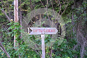 Wood sign with an arrow pointing to a gift shop, also in French - Cadeaux