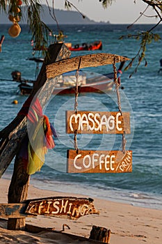 Wood sign of coffee, massage, fishing text at beautiful Thailand travel island Koh Lipe morning peace sea sand beach with sunrise