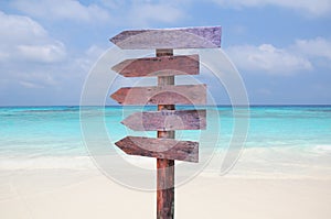 Wood signs for travel directions on the beach with sea and blue sky background