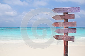 Wood signs for travel directions on the beach with sea and blue sky background