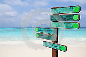 Wood signs for travel directions on the beach with sea and blue sky background