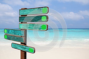 Wood signs for travel directions on the beach with sea and blue sky background
