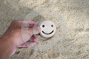 wood smile face on the sand. concept for Service rating, satisfaction concept
