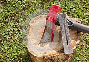 A wood splitting maul with a metal wedge on top of a wooden log