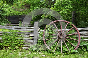 Wood spoke wagon wheel left on the wooden fence on a farmhouse