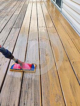 Wood stain with a paint pad on wooden deck floor