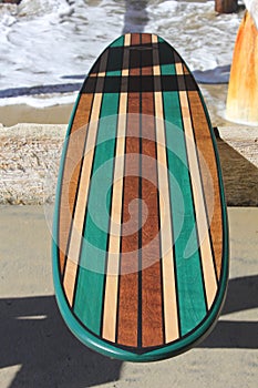Wood surfboard against California beach pier.