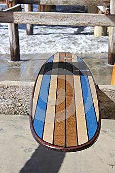 Wood surfboard against California beach pier.