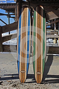 Wood surfboard against California beach pier.