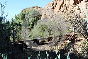 A wood, suspension bridge spanning a creek bed in the desert, sandstone mountains of Superior, Arizona