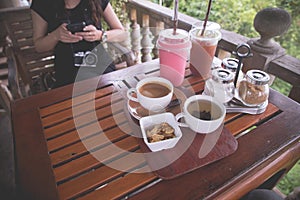 Wood table with black coffee cup and cold strawberry smoothie