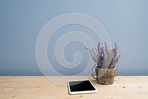 Wood table with blank screen smartphone and purple lavender flower on flowerpot.