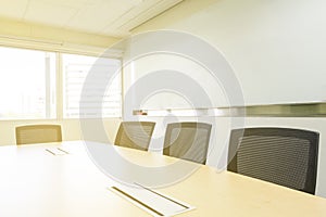 A wood table and chairs in a meeting room and sunlight through windows