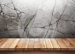 Wood table with cracked stone wall background