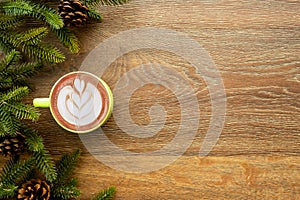 Wood table with cup of latte coffee and Christmas decoration with pine branches and pine cones. Christmas and new year celebration