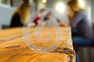 wood table edge, soft focus customers using laptops behind