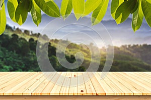 Wood table with Green leaves and Forest on the blurred background.